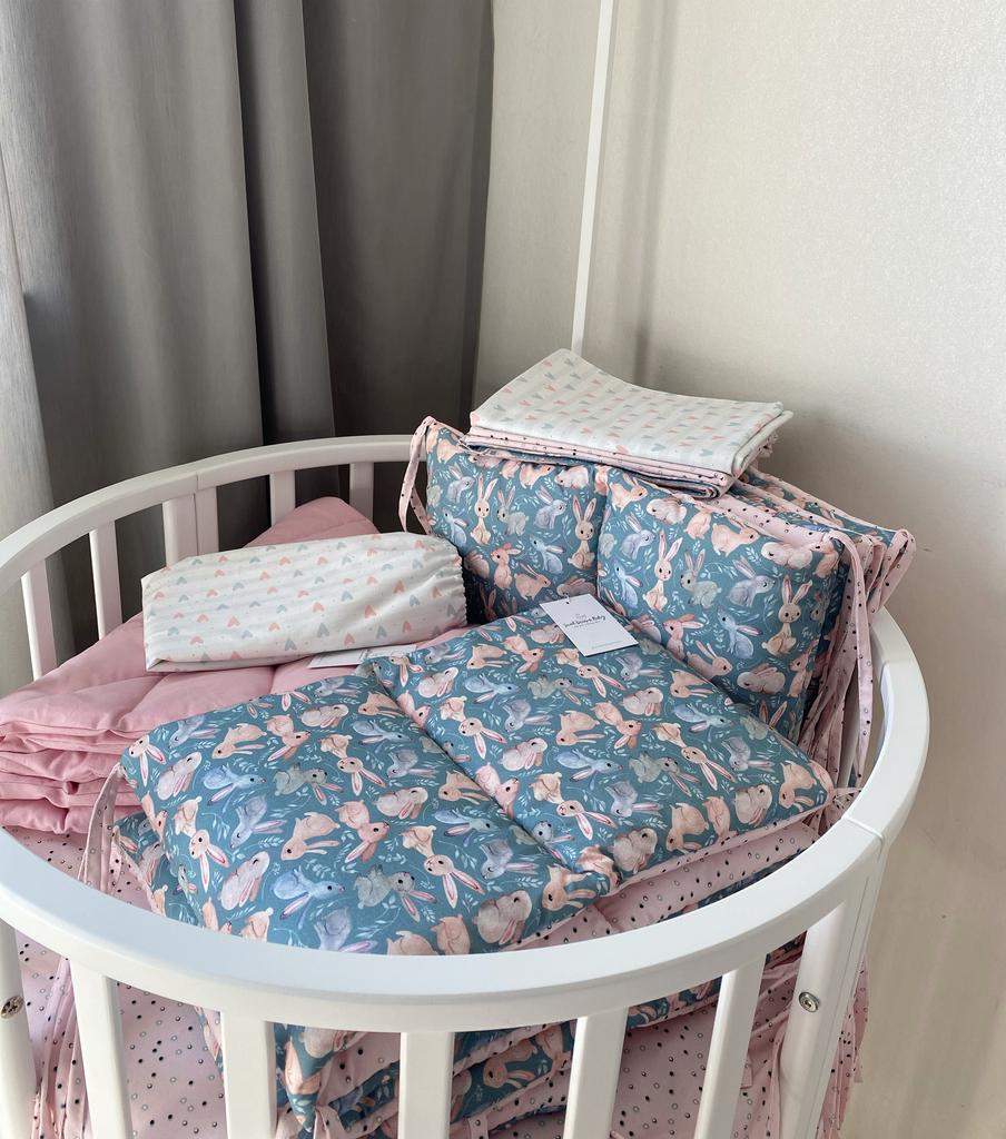 Комплект постельного белья состоящий из двух простыней на резинке, бортиков на весь периметр кроватки, двух двухсторонних простынок и коврика - одеяло (зайки на сером, точки на розовом, сердечки)