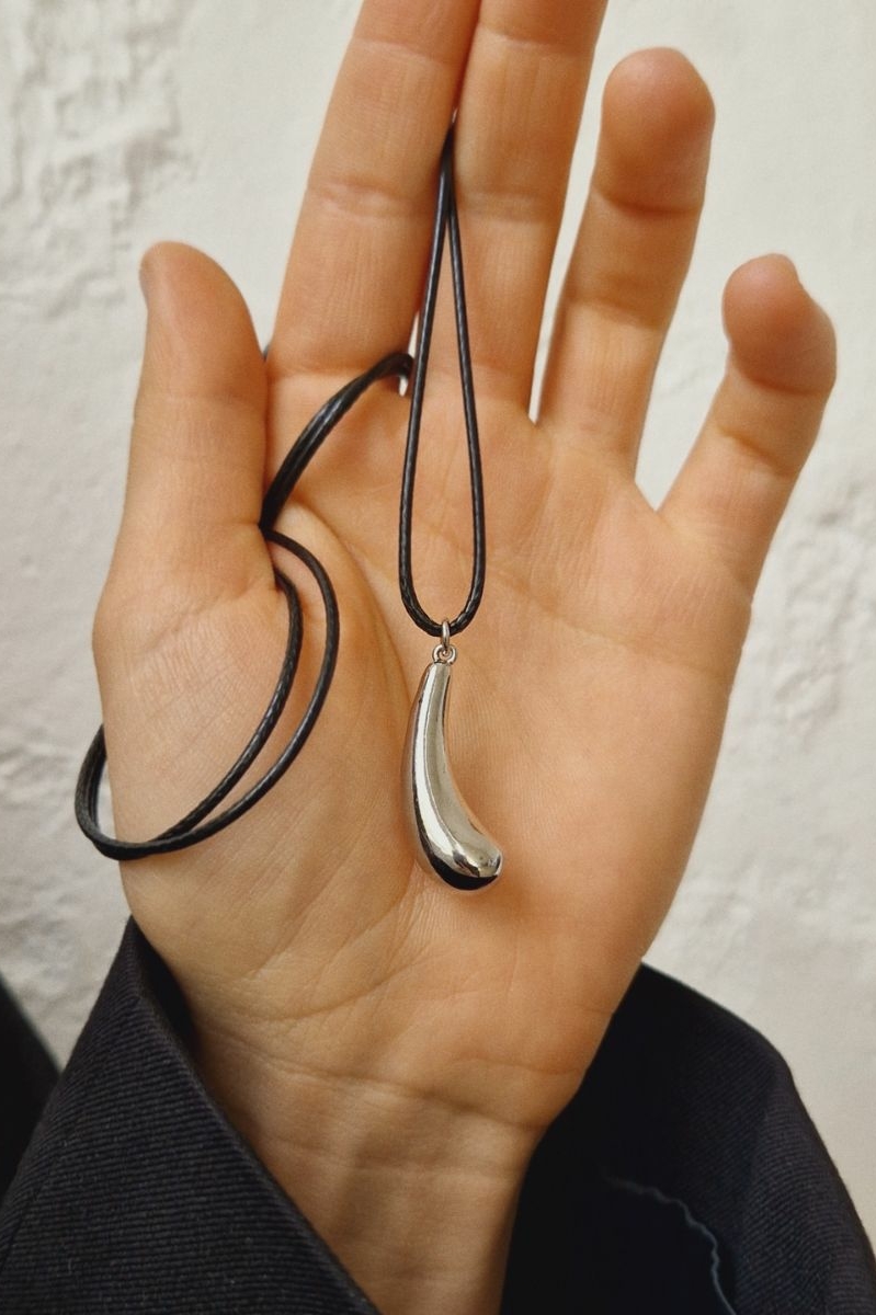 Кулон капля на шнурке в женской руке