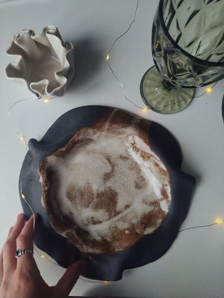 Тарелка из черной глины c изогнутыми краями