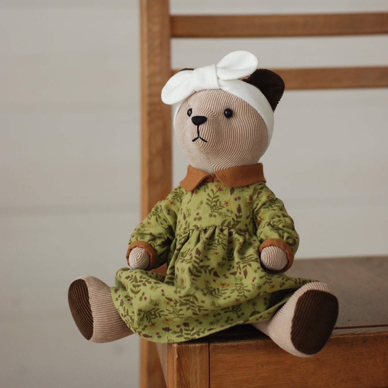 Светло-бежевый медвежонок в платье и повязке