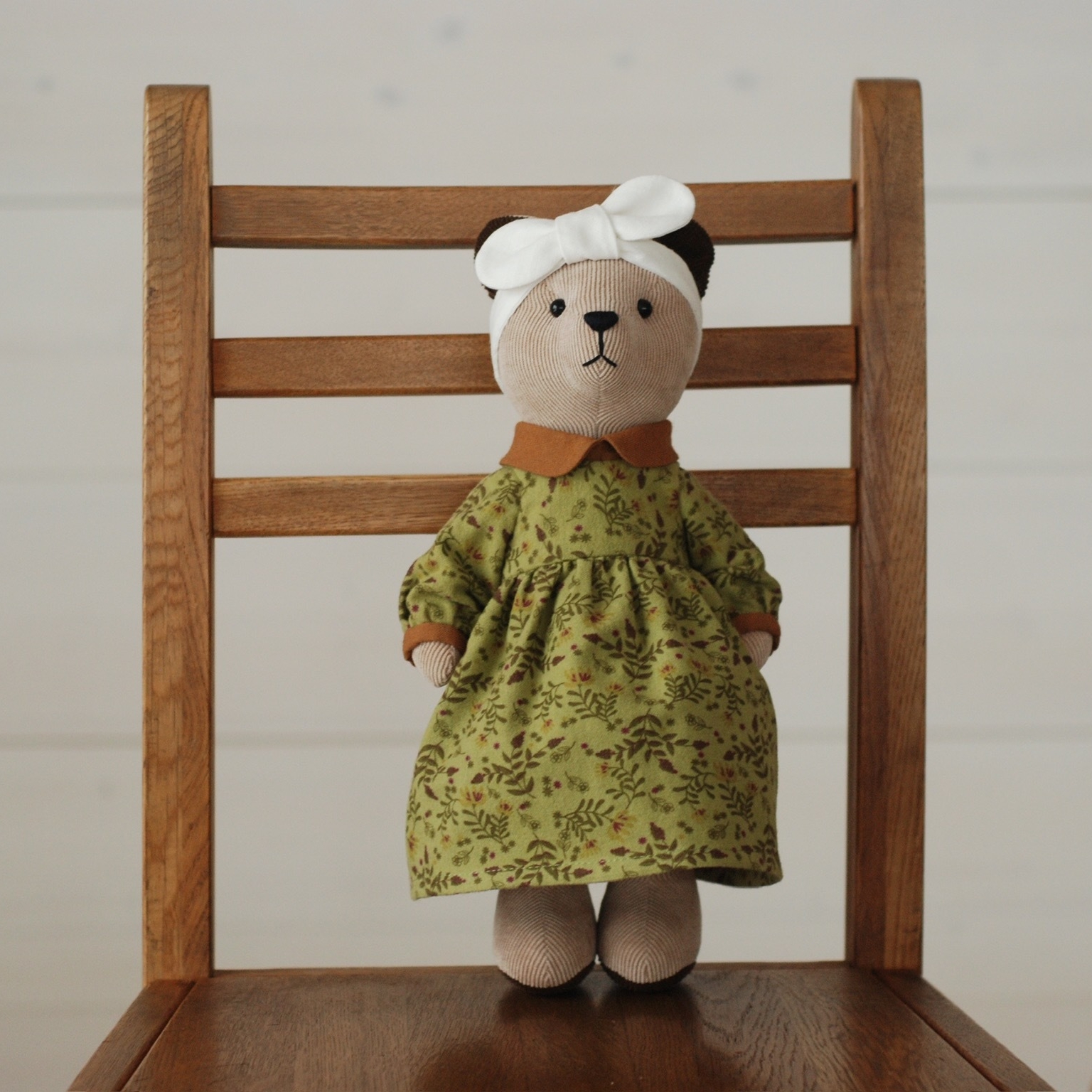 Светло-бежевый медвежонок в платье и повязке