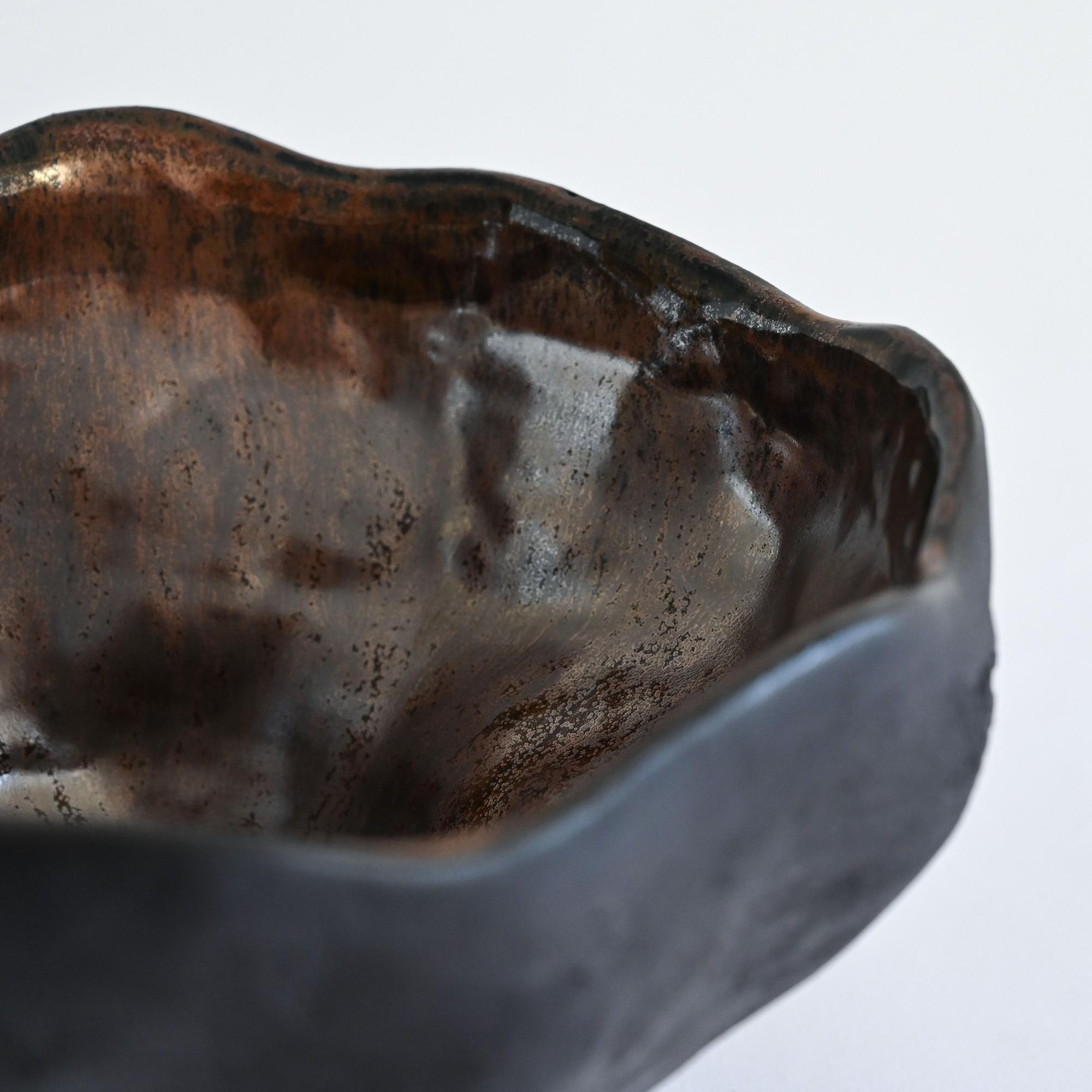 A black handmade textured vase with a metallic glaze and a wavy form details