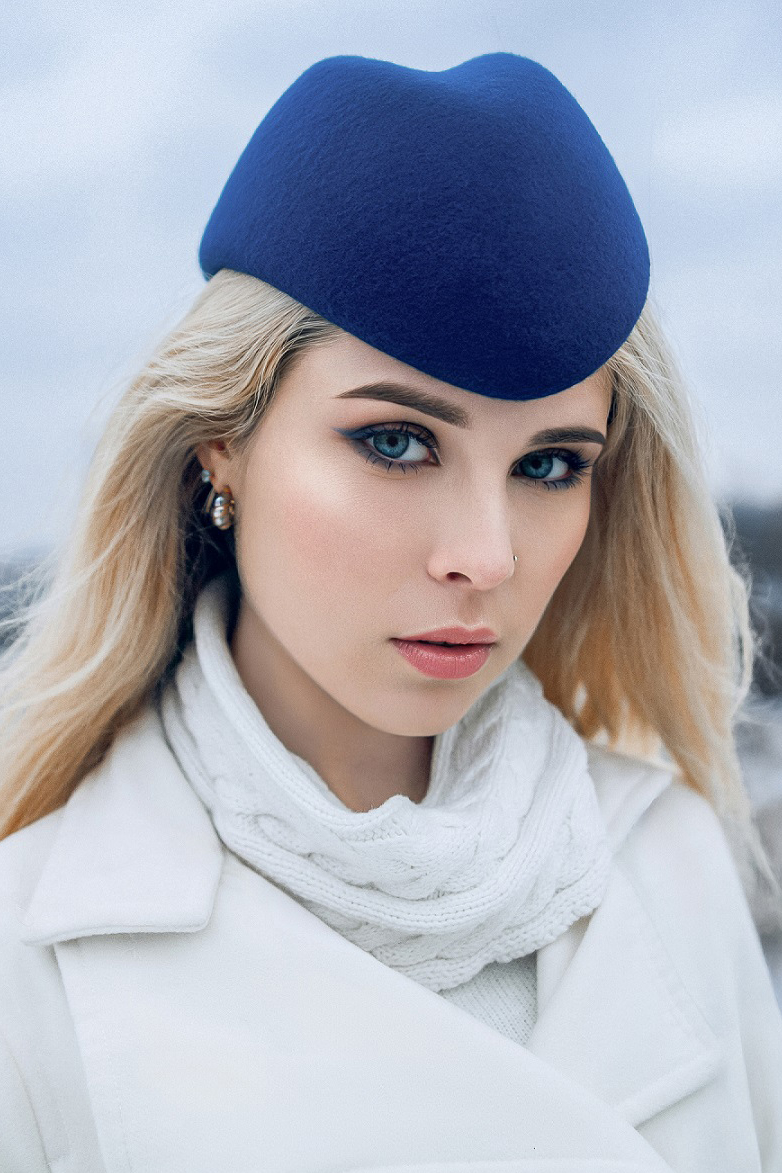 Блондинка в синей шляпке пилотке и белом пальто на фоне Санкт-Петербурга