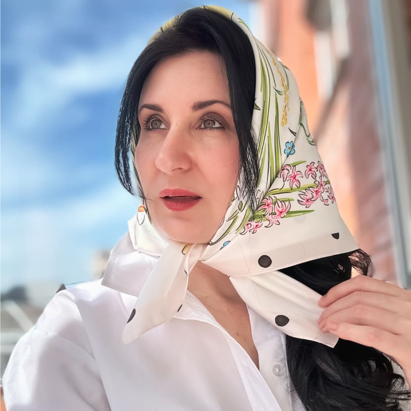 Девушка в белом платке с весенними цветами и в горошек, завязанном под подбородком.