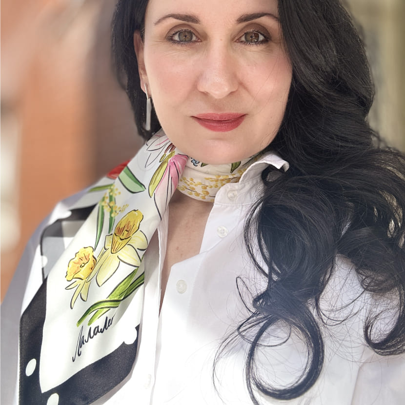 Девушка в белом платке с весенними цветами и черным кантом в горошек, завязанном на шее.