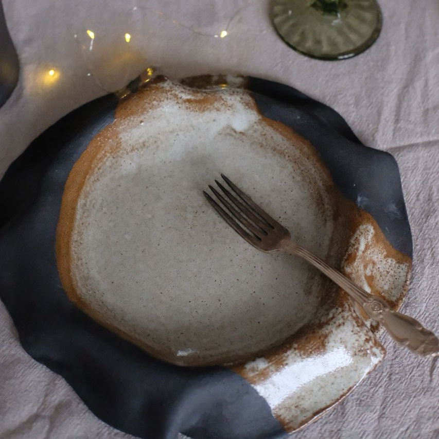 Тарелка из черной глины c изогнутыми краями