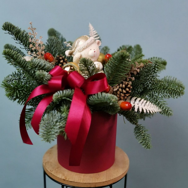 Новогодняя композиция с медвежонком, еловыми ветками и красным бантом в декоративной кашпо