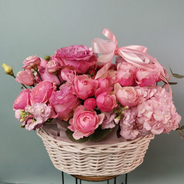 Плетёная корзина с розовыми пионовидными розами, гортензией и лизиантусом