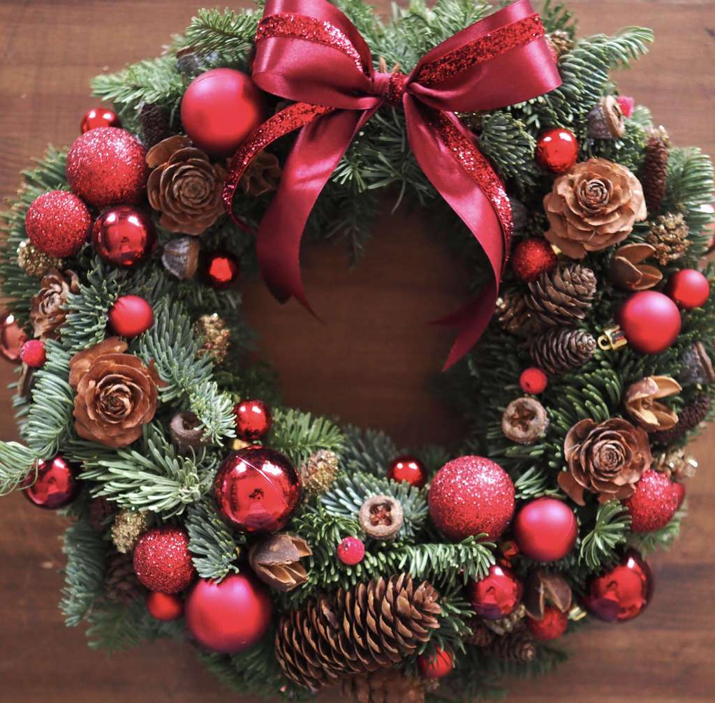 рождественский венок с шишками и красными декоративными элементами