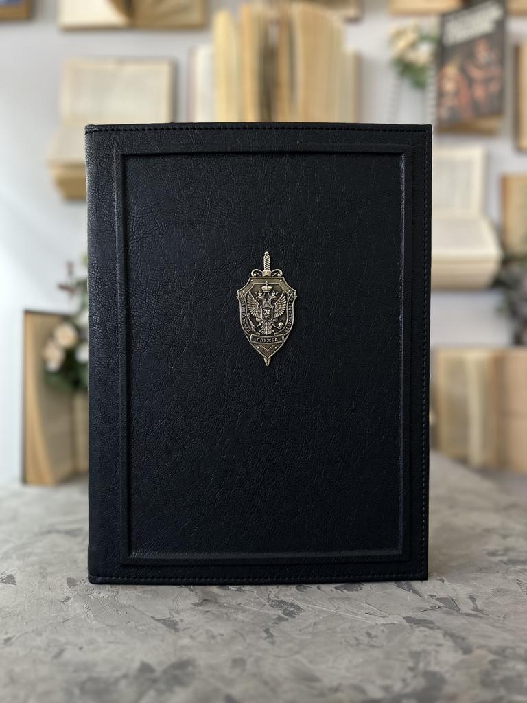 Папка на подпись в черной эко-коже с металлическим гербом ФСБ и фактурным бортиком по периметру. Строгий, авторитетный дизайн для официального использования