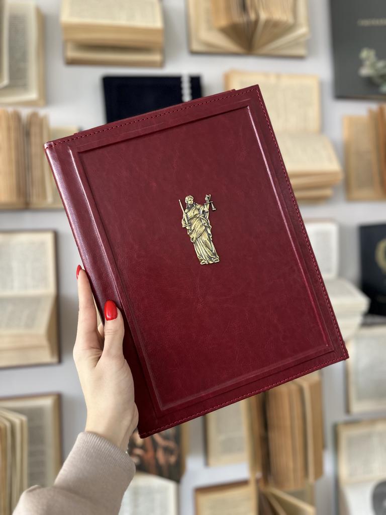 Папка на подпись бордового цвета с металлической фигурой Фемиды и фактурным бортиком по периметру. Символ справедливости, строгий дизайн для юристов.