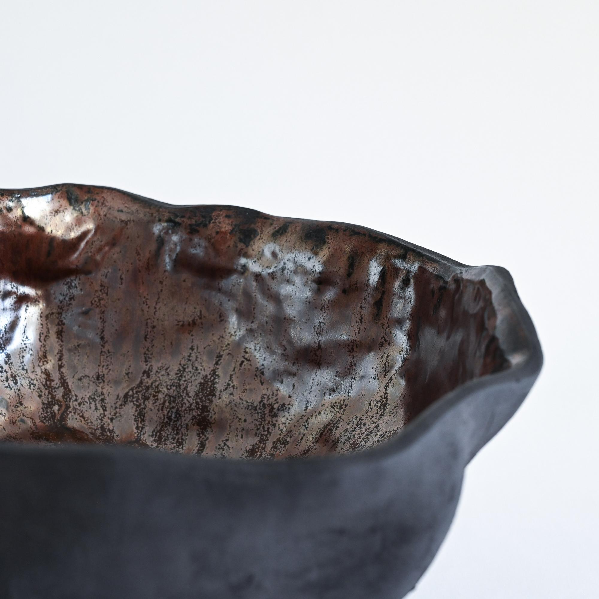 A black handmade textured vase with a metallic glaze and a wavy form details