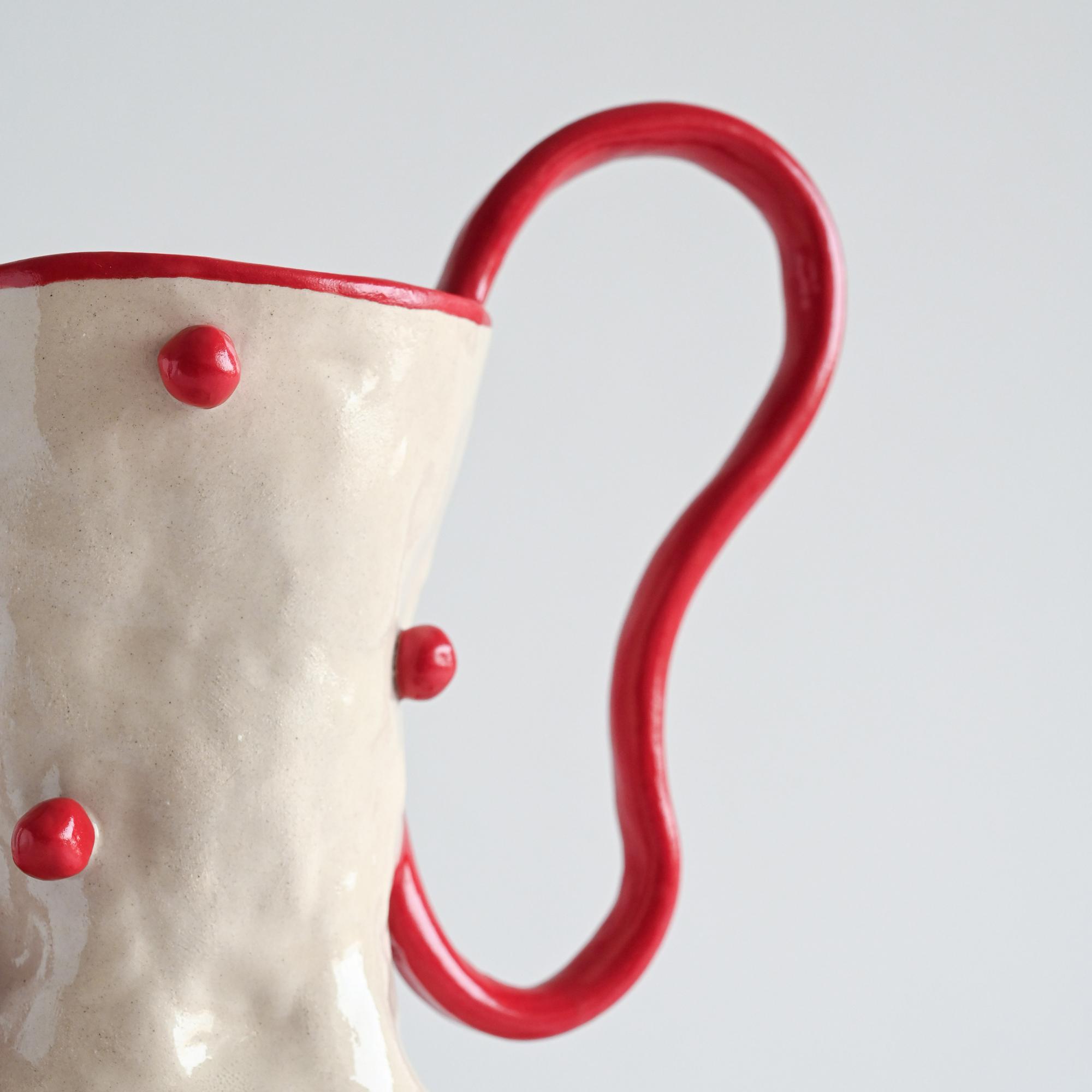 Handmade ceramic white vase with red beads and curved handles details