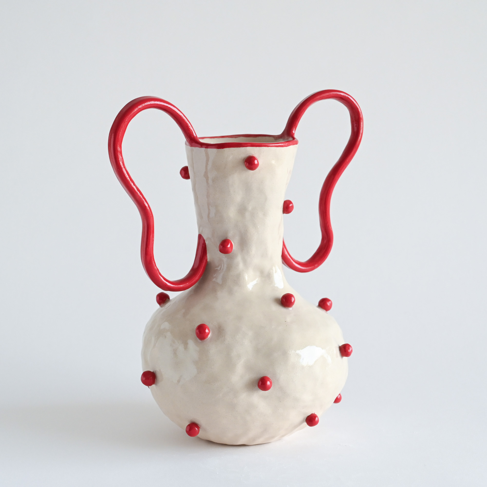 Handmade ceramic white vase with red beads and curved handles