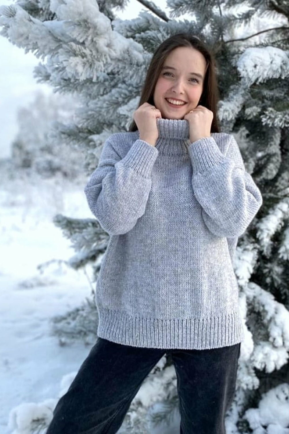 Женский свитер North светло-серого цвета, модель стоит на фоне заснеженных ёлок