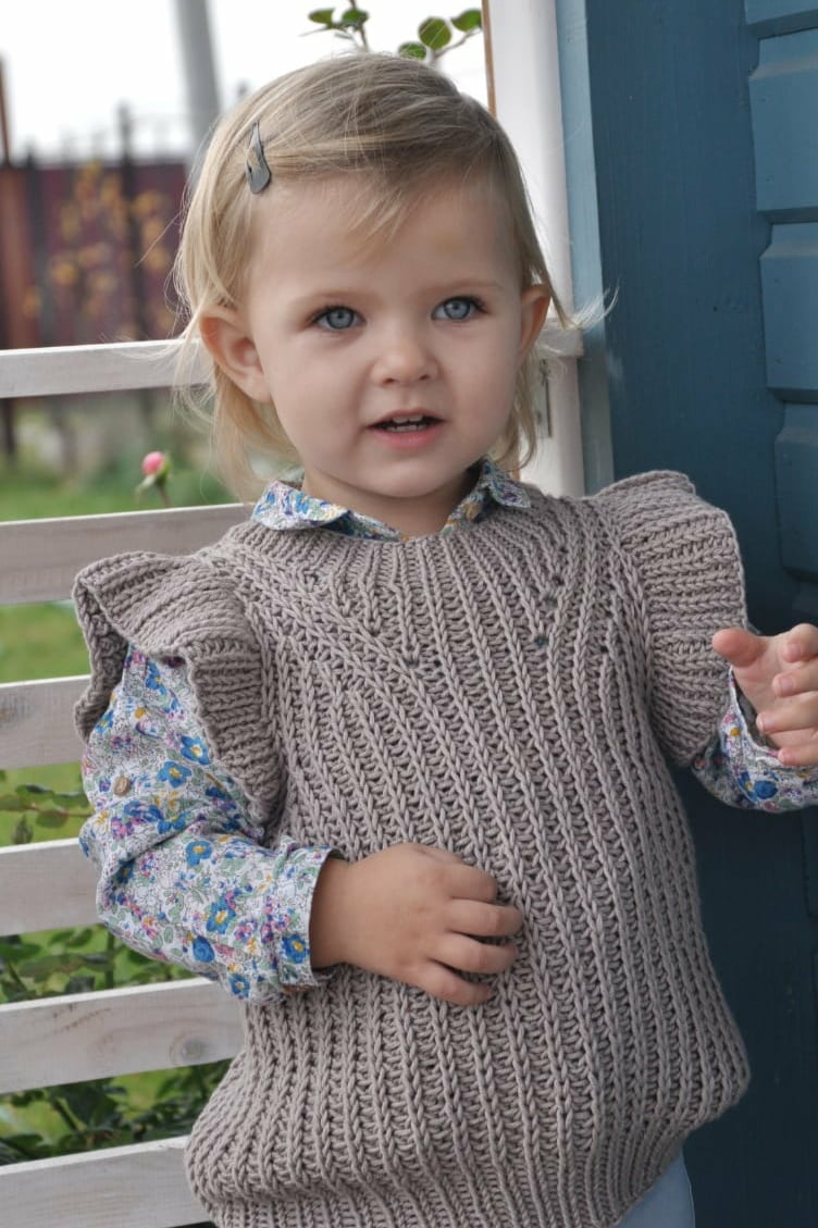 Девочка в вязаном жилете с ажурным узором – результат мастер-класса по детской одежде спицами