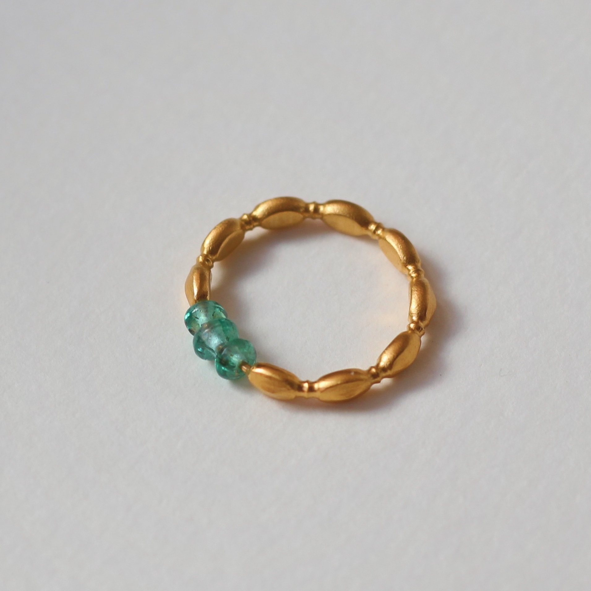 Зерно - кольцо позолоченное с гладкими синтезированными изумрудами