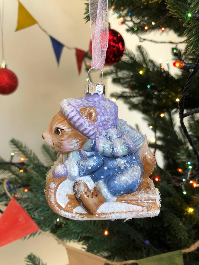 Елочная игрушка белка на санках в сиреневой шапке