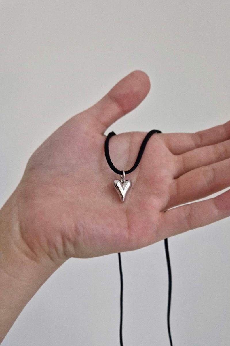 кулон с сердечком на шнурке в женской руке