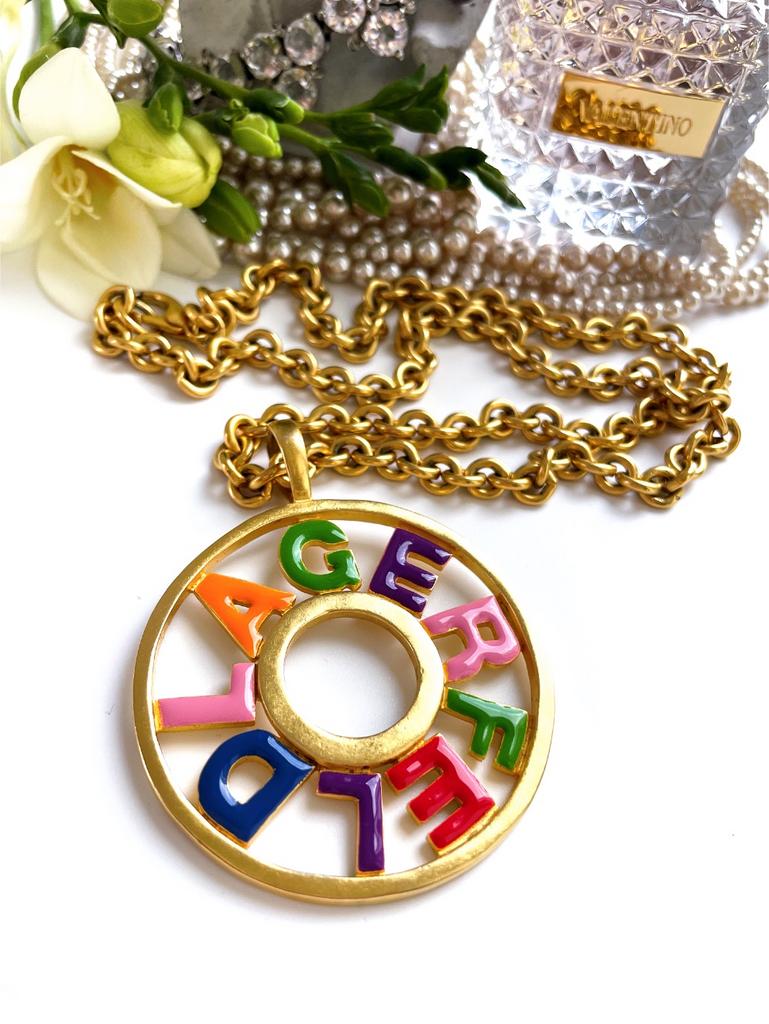 Колье с круглым кулоном и разноцветными буквами